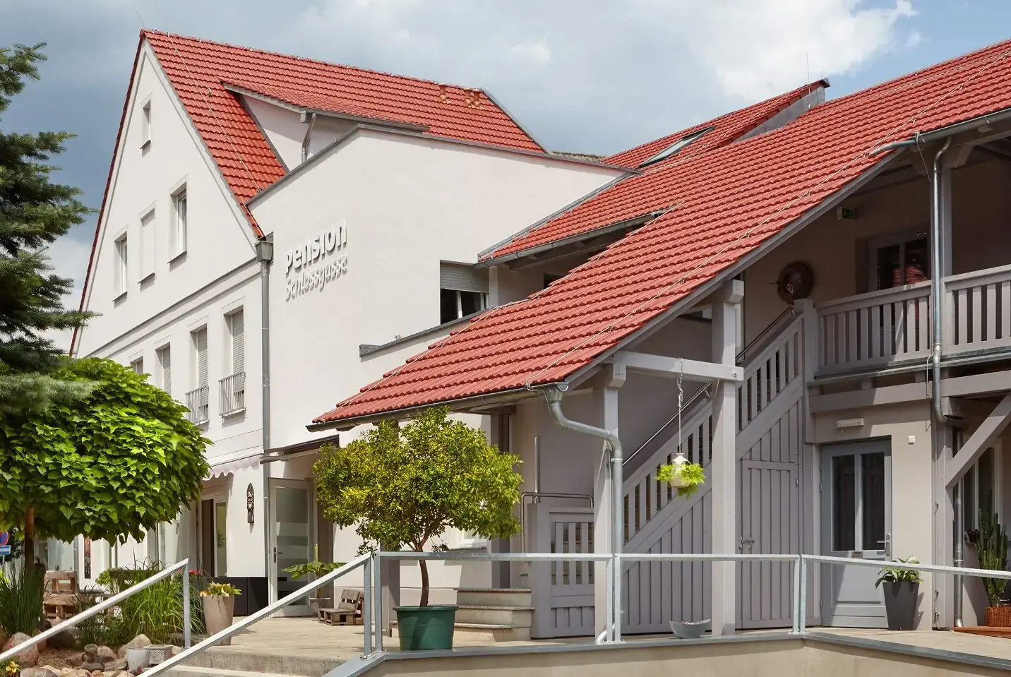 Fassade der Pension mit rotem Ziegeldach und Laubengang