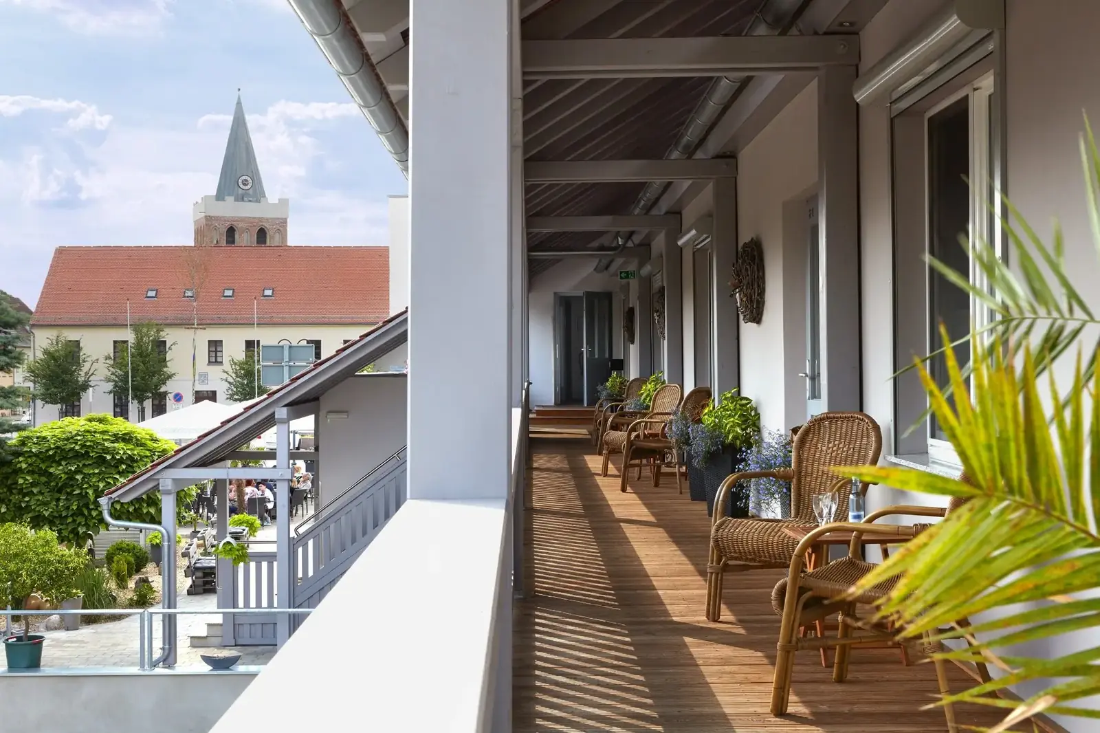 Laubengang mit Korbstühlen und Blick zur Kirche von Lieberose